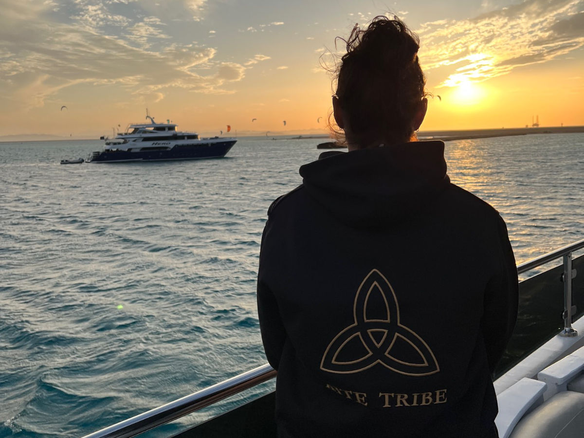 Kite Tribe Kite Safari group of people on the beach watching a kitesurfer jump. everyone is wearing a kite tribe tshirt