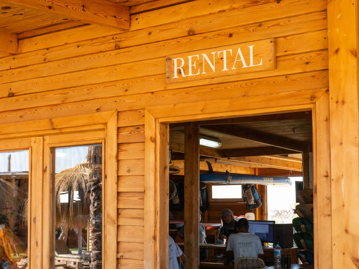 kitesurfing_rental group of people on the beach watching a kitesurfer jump. everyone is wearing a kite tribe tshirt
